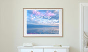 White dresser with a framed blue photograph of Lake Geneva bove it in a room with an open door.