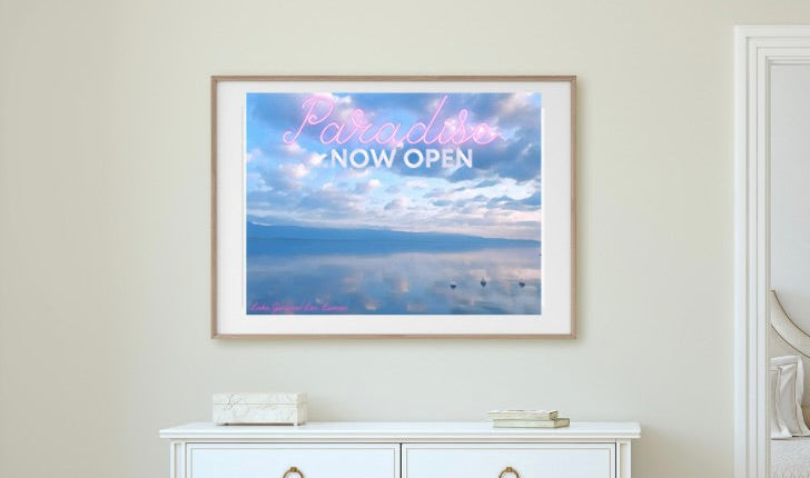White dresser with a framed blue photograph of Lake Geneva bove it in a room with an open door.