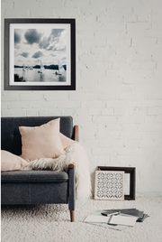 Modern living room with a gray sofa, framed picture, and decorative items against a white brick wall.