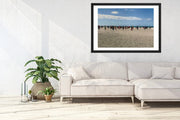 White sectional sofa in a living room with a framed picture of a beach scene on the wall.