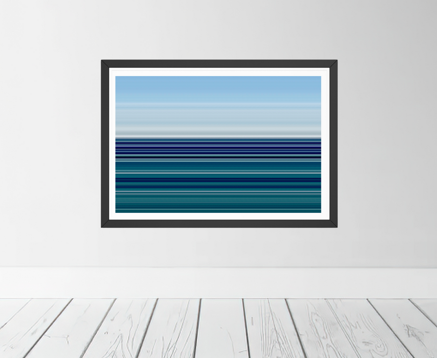 A framed horizontal art print featuring blue and teal ocean waves, displayed on a light gray wall above a white wood plank floor.