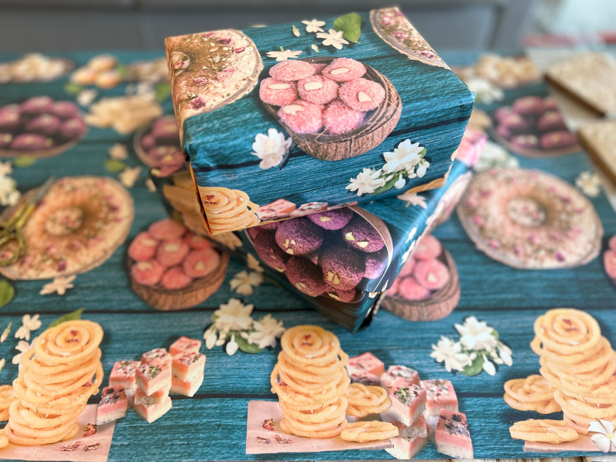 A vibrant wrapping paper featuring traditional Indian sweets like ladoos, barfi, and jalebis on a rich teal wooden background. Decorated with jasmine flowers and intricate details, this seamless pattern adds a festive, cultural touch, perfect for celebrations.