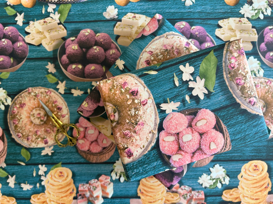 A vibrant wrapping paper featuring traditional Indian sweets like ladoos, barfi, and jalebis on a rich teal wooden background. Decorated with jasmine flowers and intricate details, this seamless pattern adds a festive, cultural touch, perfect for celebrations.