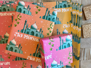 A festive Eid wrapping paper featuring a majestic mosque on a pink-to-orange graduated background. Adorned with twinkling stars, crescent moons, and elegant Eid Mubarak text, this design captures the joy and spirituality of Eid celebrations.