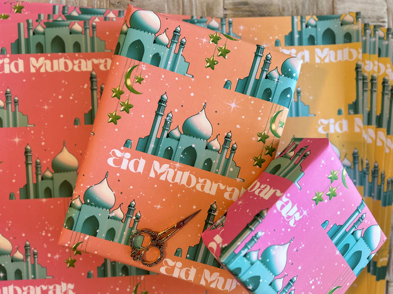A festive Eid wrapping paper featuring a majestic mosque on a pink-to-orange graduated background. Adorned with twinkling stars, crescent moons, and elegant Eid Mubarak text, this design captures the joy and spirituality of Eid celebrations.
