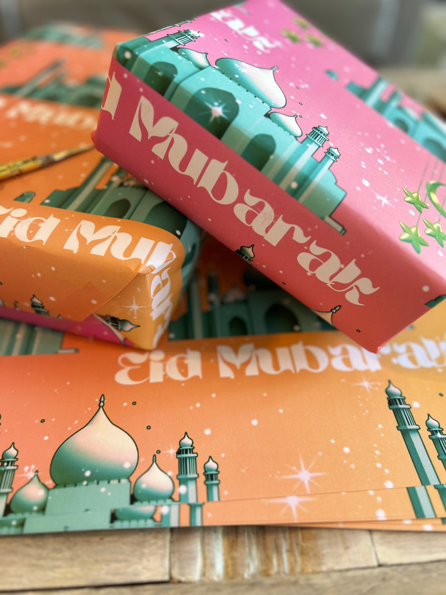 A festive Eid wrapping paper featuring a majestic mosque on a pink-to-orange graduated background. Adorned with twinkling stars, crescent moons, and elegant Eid Mubarak text, this design captures the joy and spirituality of Eid celebrations.
