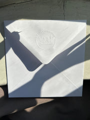 Hand-embossed recycled white accompanying envelope.