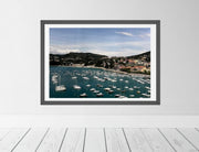 Framed photograph of a harbor scene on a white wall.