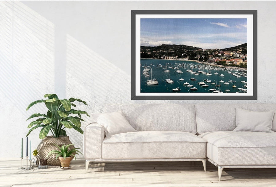 Framed photograph of a coastal scene on a wall above a white sofa.