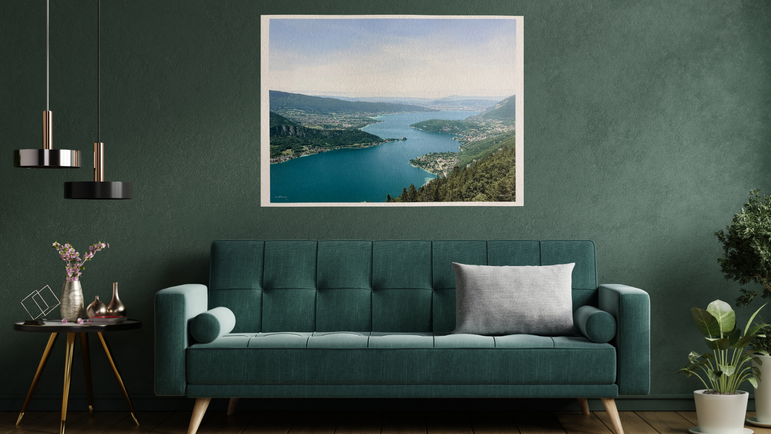 Modern living room with a green sofa, framed picture of a lake, and decorative plants.