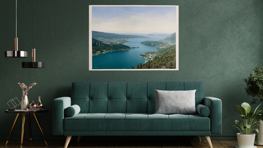 Modern living room with a green sofa, framed picture of a lake, and decorative plants.